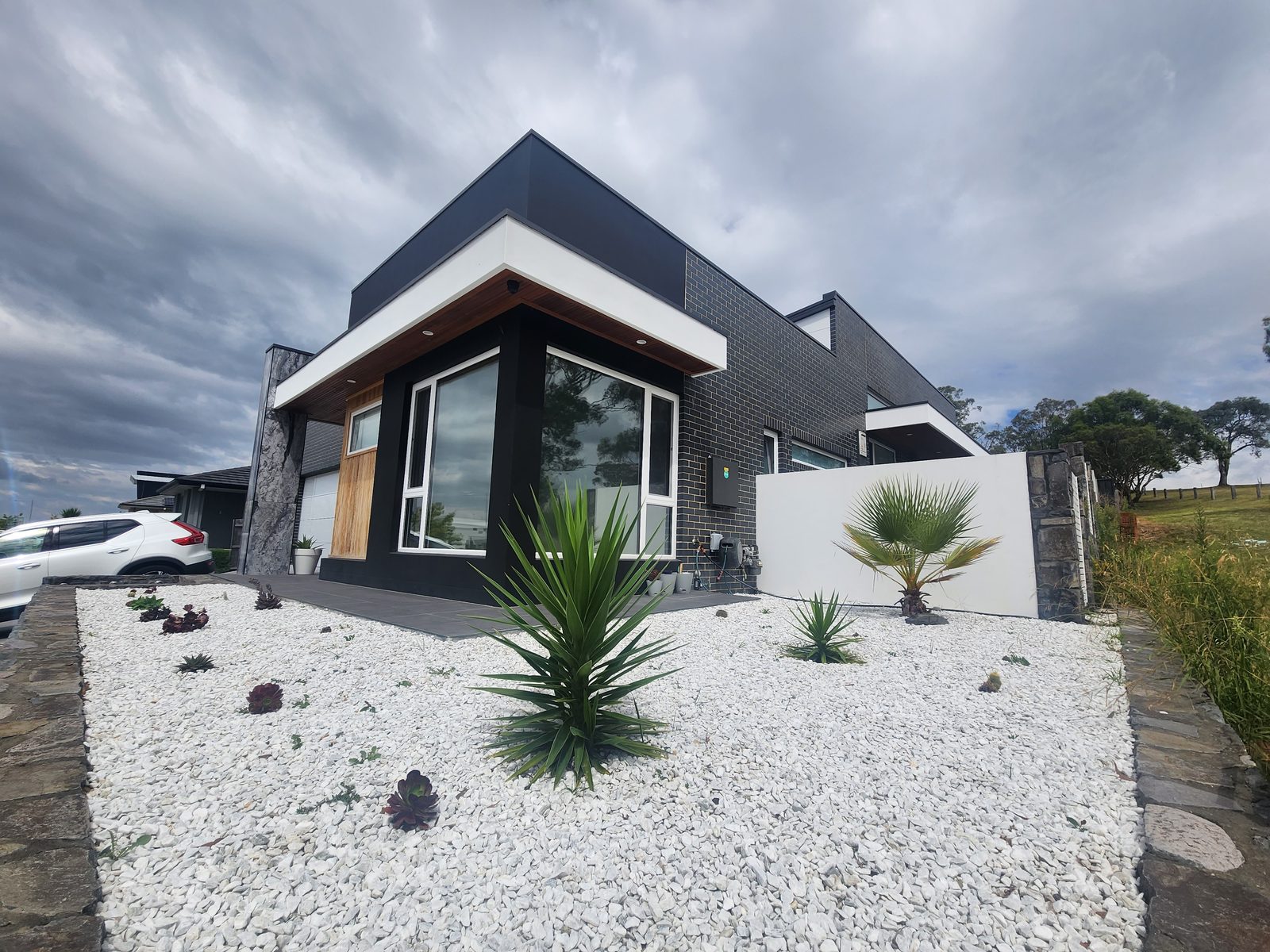 Modern home exterior with charcoal cladding and rock garden